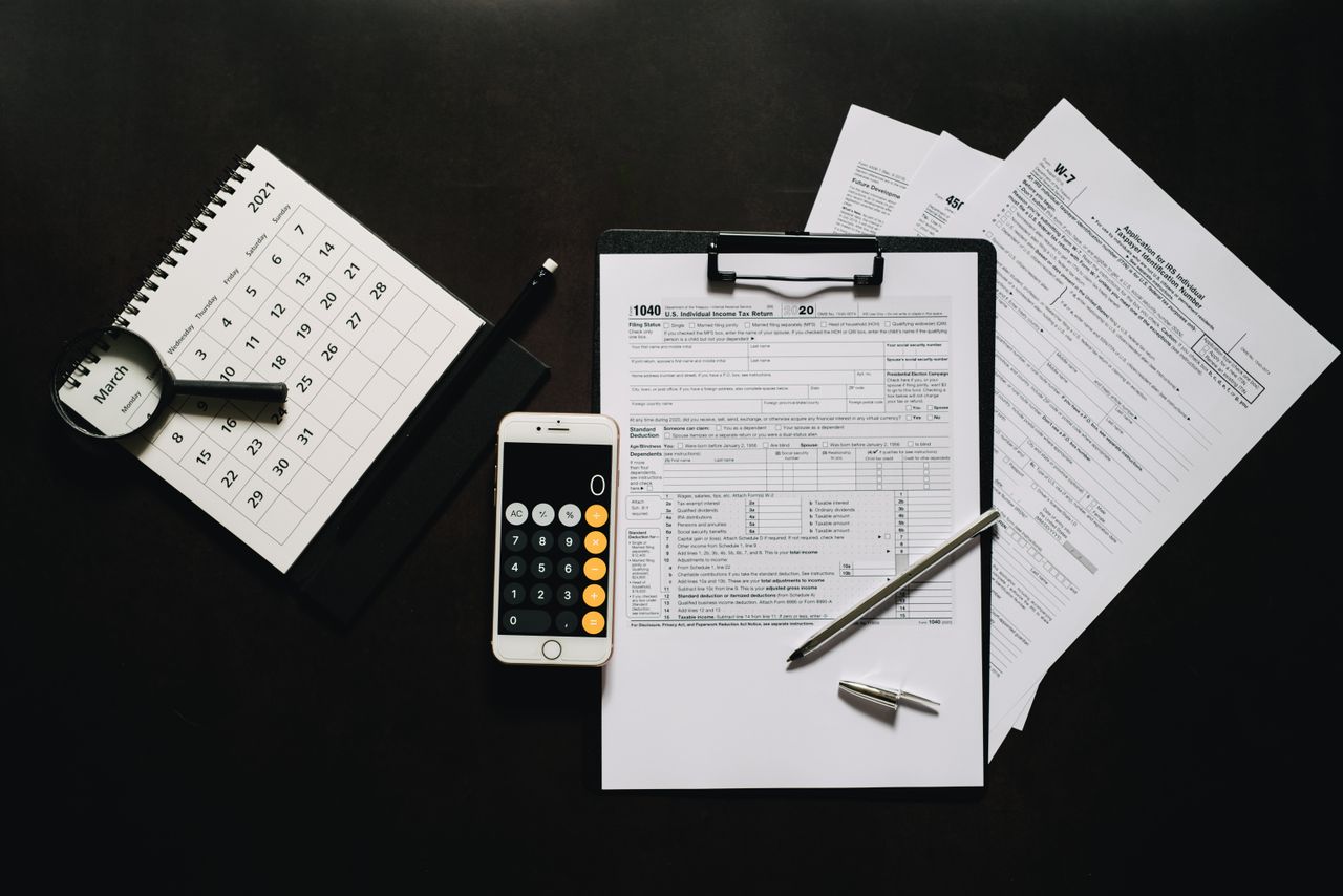 our-experience Flat lay of financial tools for tax preparation including forms, calculator, and calendar.
